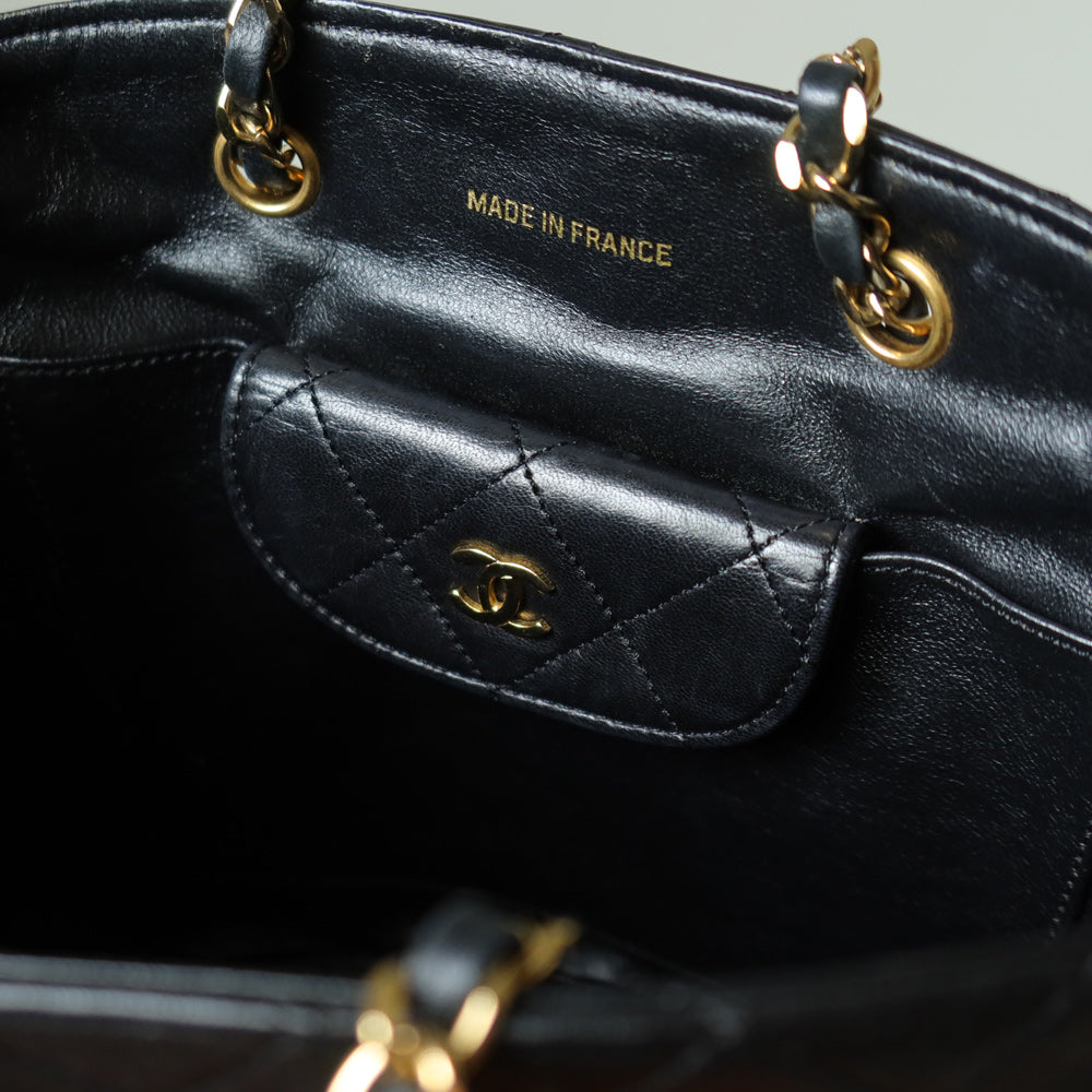 Black leather handbag with gold hardware, featuring the Chanel logo inside the bag.