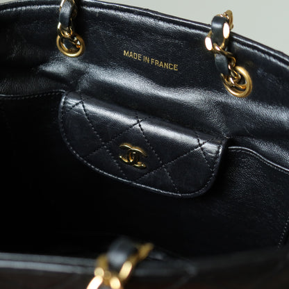 Black leather handbag with gold hardware, featuring the Chanel logo inside the bag.