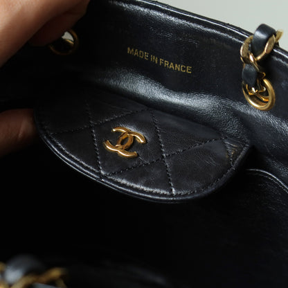 Close-up of vintage chanel black quilted handbag with gold hardware, featuring the Chanel CC logo.